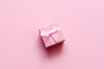 Pink gift box with bow on pink pastel background. Festive backdrop. Top view. Copy space.