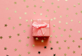 Gift box with holographic golden stars. Living Coral - Color of the Year 2019. Festive backdrop. Top view.