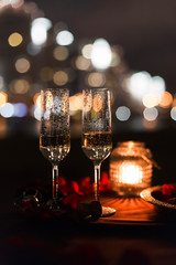 Romantic luxury evening with champagne setting with two glasses. rose petails and candles. Champagne for romantic celebrations or New Year party and enjoy for special moments. Bokeh background.