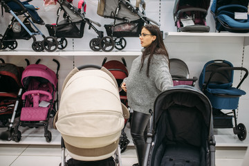 Pregnant woman looking for pushchair in store