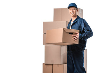 handsome mover in uniform carrying cardboard box and looking at camera isolated on white with copy space