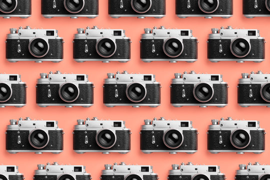 Photo cameras organized in a row over coral color background