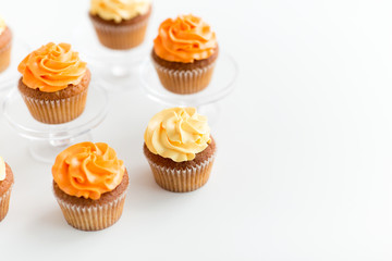 food, pastry and sweets concept - cupcakes with buttercream frosting on glass confectionery stand over white background