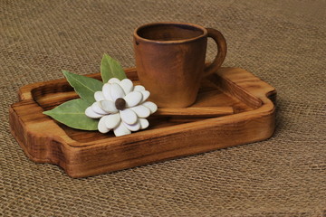 Exclusive homemade flower from pumpkin seeds and bay leaf with clay cup on wooden tray on rough jute canvas. Concept for birthday, Mother's Day, Valentine's Day.