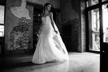 Fototapeta na wymiar Model posing in a white long wedding dress indoors by the window. Advertising of wedding dresses