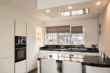 Modern luxury kitchen with light colors, kitchen island and granite table top in an architecture-built house