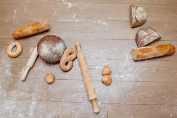 On the wooden floor are bread, flour and rolling pin.