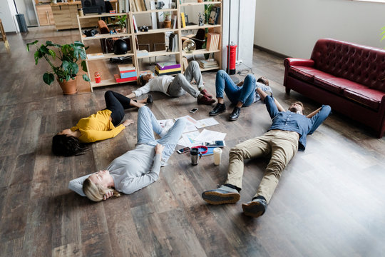 Business team lying on the floor surrounded by documents in loft office