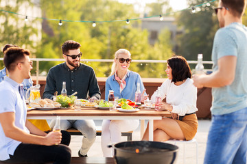 leisure and people concept - happy friends having bbq party on rooftop in summer
