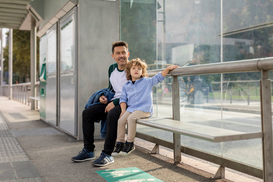 Father and son sitting at tram stop in the city
