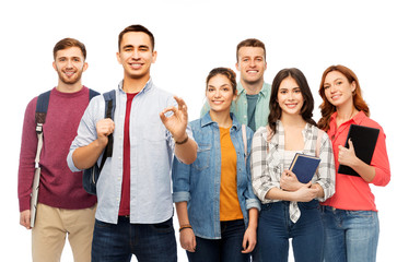 Obraz premium education, high school and people concept - group of smiling students with books showing ok hand sign over white background