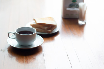 A Cup of coffee with toast on a wooden table for breakfast time