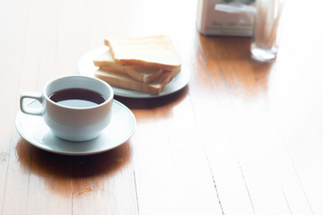 A Cup of coffee with toast on a wooden table for breakfast time