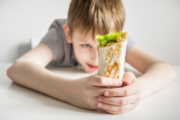 Teen boy looks at junk food shawarma. Selective focus on shawarma