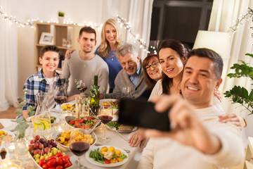 celebration, holidays and people concept - happy family having dinner party at home and taking selfie by smartphone