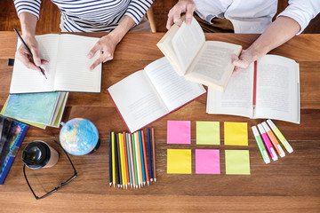 High school or college student group sitting at desk in library studying and reading, doing homework and lesson practice preparing exam to entrance, education concept