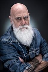 studio portrait of a bald man with tattooed arms and white beard