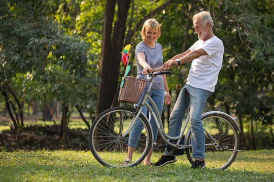 Happy senior couple relaxing at park  walking with bike and talking  together in morning time. old people in the autumn park . Elderly resting .mature relationships. family. romantic