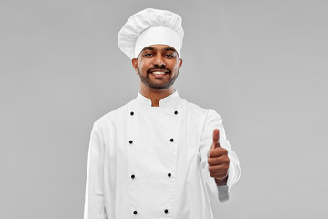 cooking, profession and people concept - happy male indian chef in toque showing thumbs up over grey background