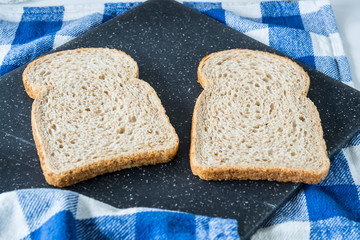 two slice of brown bread, wheat, wholegrain on grey cutting boad