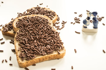 two slices of bread with typical dutch chocolate hail, hagelslag . Against white background, Delfts blue souvenir. 