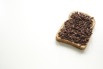slice of bread with typical dutch chocolate hail, hagelslag . Against white background, space for text