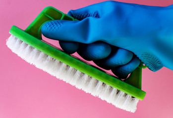 Washing concept. A hand with brush isolated on pink background. Worker cleaning. Cleaning with the foam and brush. Cleaning concept. Hand in blue protective rubber glove