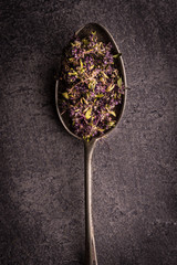 Dry Tea Leafs in Rustic Spoon on Dark Stone Background