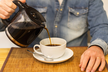 Hombre sirviéndose café. Vista de frente y de cerca. Concepto: Desayuno