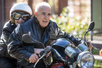 Fototapeta na wymiar Coppia di anziani vanno in giro sulla loro Motocicletta d'epoca