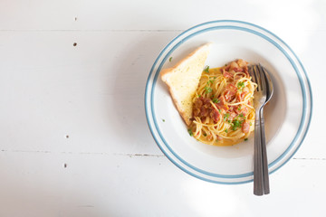 Spaghetti Carbonara with ham, cheese and bread on white table