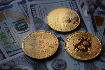 Three Gold Bitcoin Coins on US Dollars.