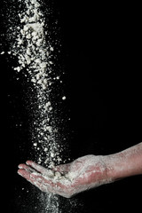 close up flour falling in mans hand, against black background 2