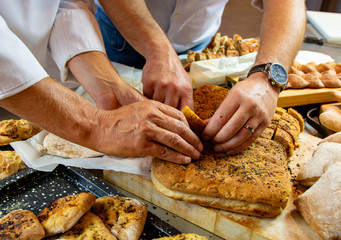 Hands touching breads on wooden cutting board