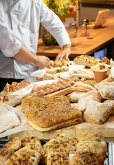 Assortment of artisian breads with hands of chef in background