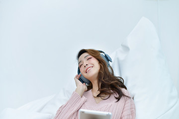 Winter Concept. Cute Asian girl in winter dress. Beautiful women in winter clothes are listening to music in the bedroom.