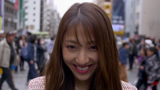 Japanese woman smiling in busy tourist area in Dotonbori Osaka, 4K