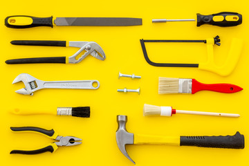 constructor desk with set of building implements and brushes yellow background top view pattern