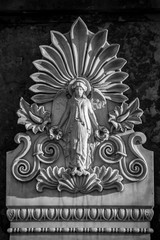 Fototapeta na wymiar Verwitterte Relief Plakette aus Stein eines weiblichen Engel an einer Mauer auf dem Dorotheenstädtischen Friedhof in Berlin