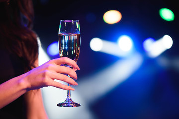 holidays, nightlife, drinks, people and luxury concept - beautiful young woman drinking champagne at party over lights background.