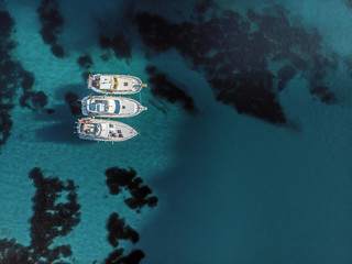Aerial view of three white yatches anchored together over crystal clear water. Relaxing vacations concept. © DDRENDER