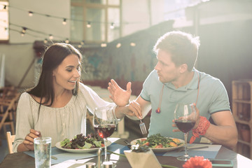 Shameless long-haired girl stealing pieces of salad from plate
