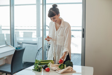 Happy healthy girl doing photo of fresh vegetables that she bought on a local farm market to post it in her social media and tell friends about sustainable shopping and zero waste food shopping