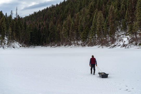 Man pulling sled on snowy landscape