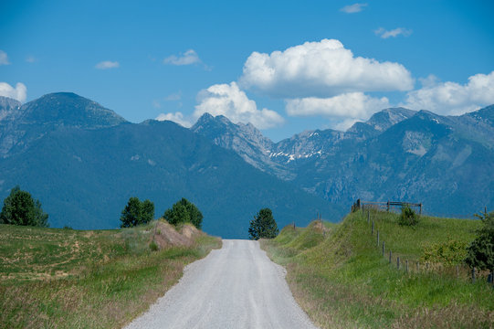 View of empty road passing through grassy landscape against mountains