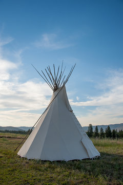 View of tipi on grassy landscape against cloudy sky