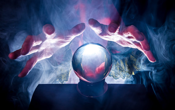 a fortune teller holds her hands over a crystal ball