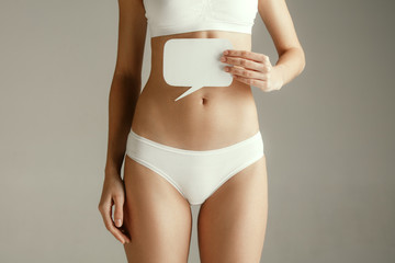 Woman health. Female model holding empty card near stomach. Young adult girl with paper for sign or...