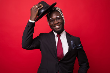 Naklejka premium Afro american business man in suit holding hat isolated on red background