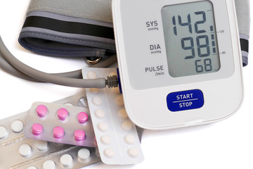 automatic blood pressure meter and pills on white background